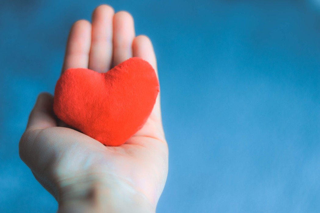 close-up-shot-of-hand-holding-soft-red-heart-on-blue-background-happy-valentine-love-care_t20_983EaO